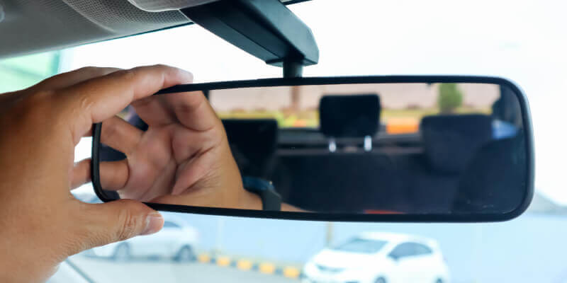 Hand adjusting the rearview mirror in car