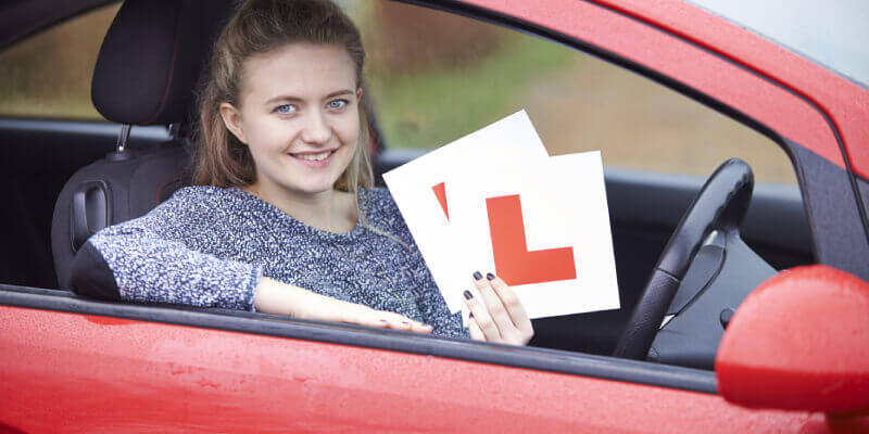 Girl in a car holding L-plates