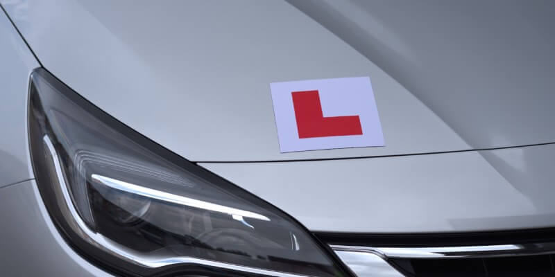 L-plate sticked on a silver car bonnet