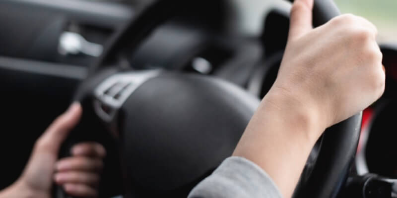 Both hands gripping steering wheel to turn it